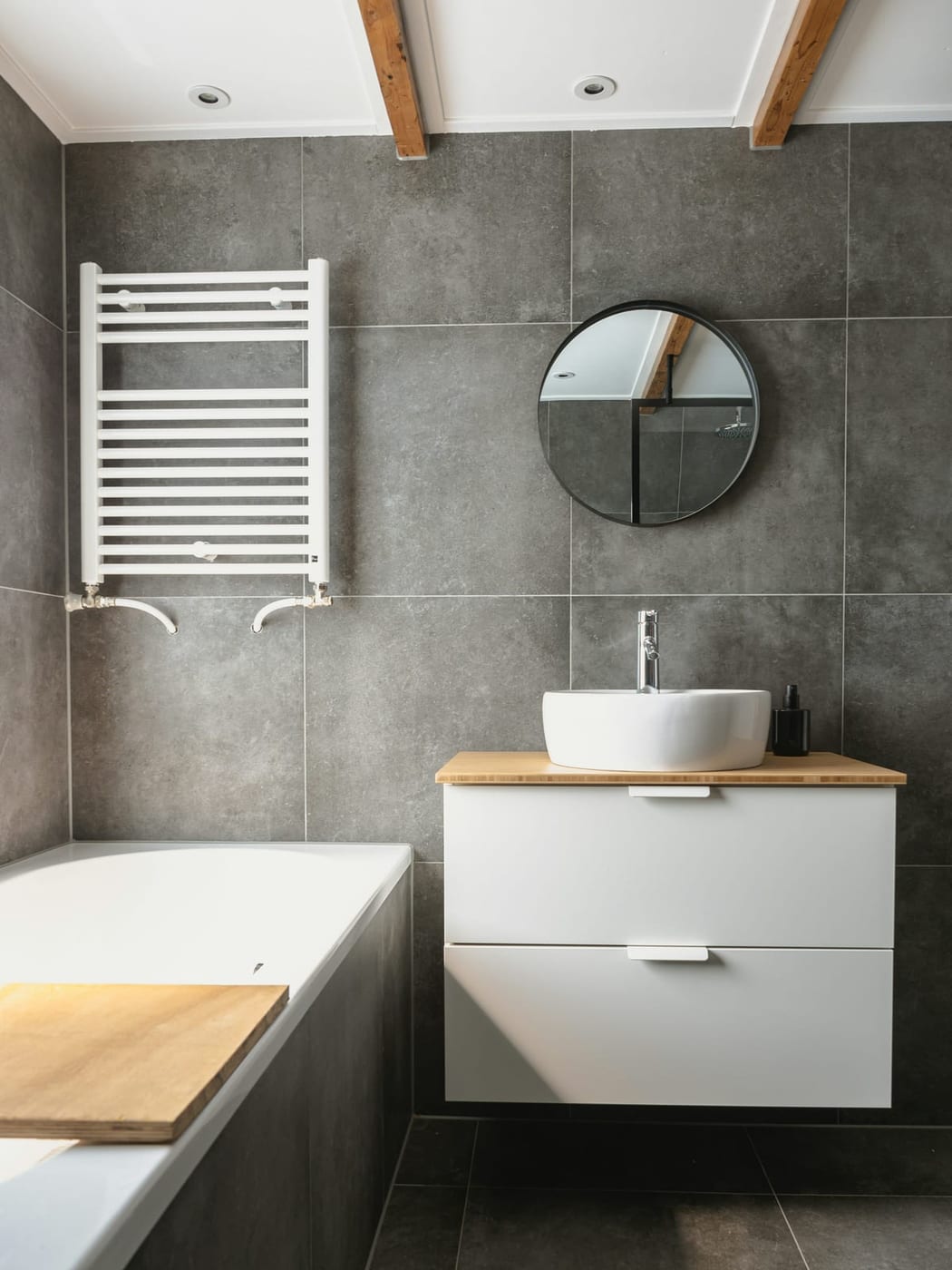 Badezimmer mit großformatigen grauen Wandfliesen, Waschtisch und Handtuchheizkörper