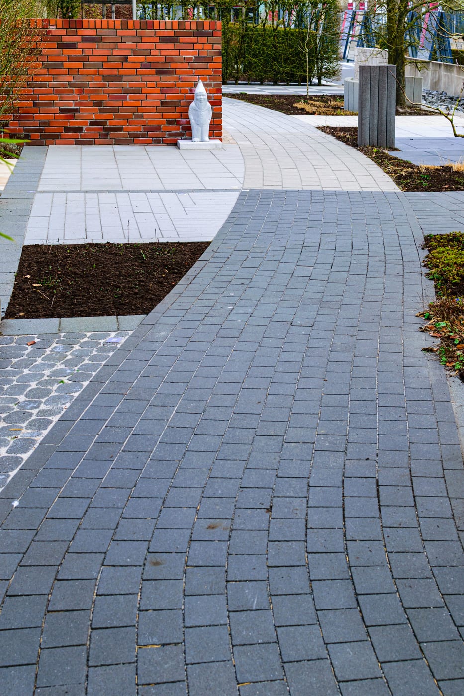 Verlegter Plattenbelag als Gartenweg entlang eines Beetstreifens